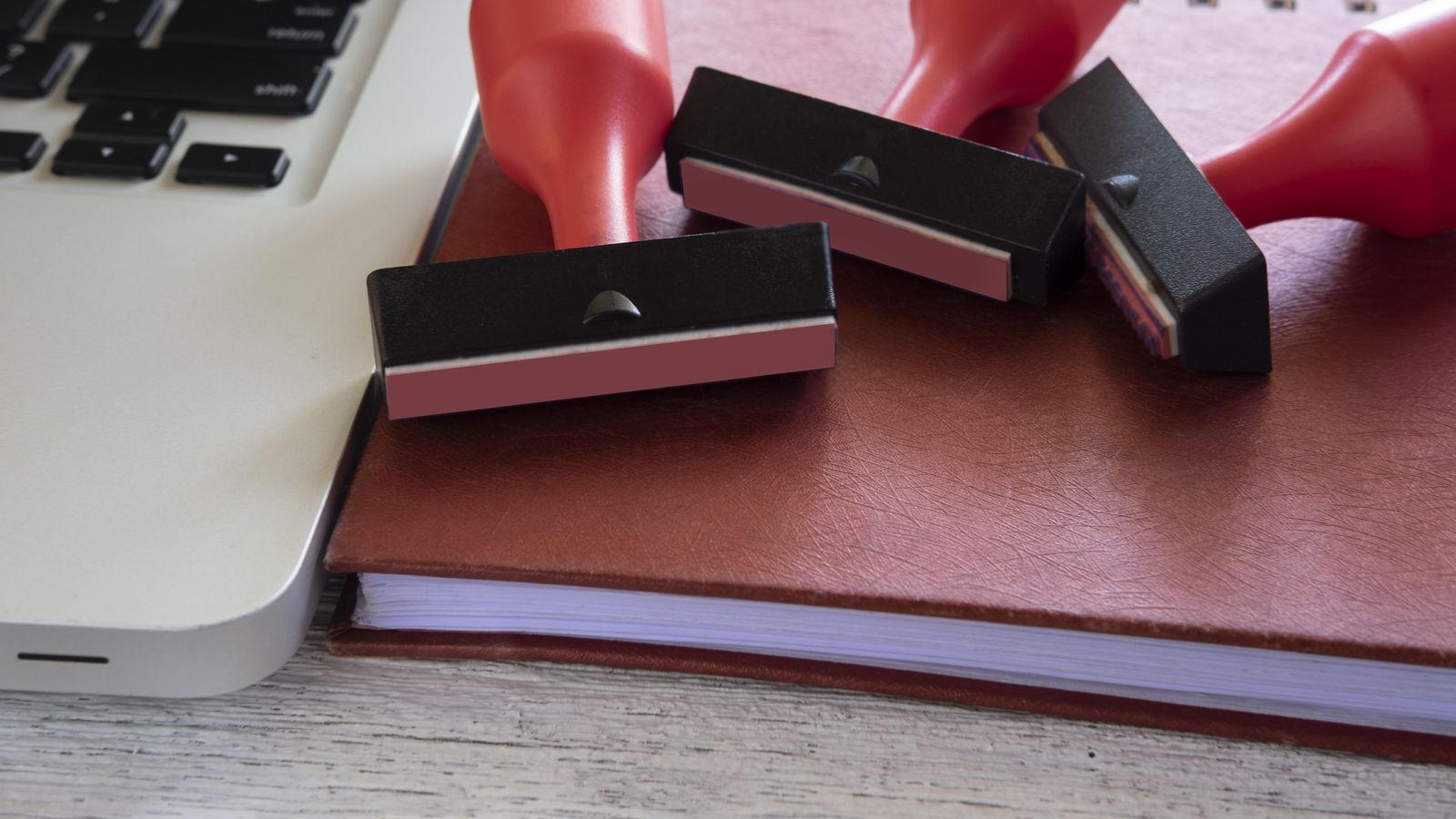 Open laptop on a workbench beside a USB drive and a small toolkit